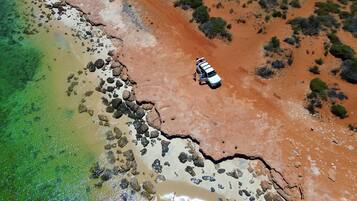 An aerial view of a coastal area with a white vehicle parked near the shoreline.