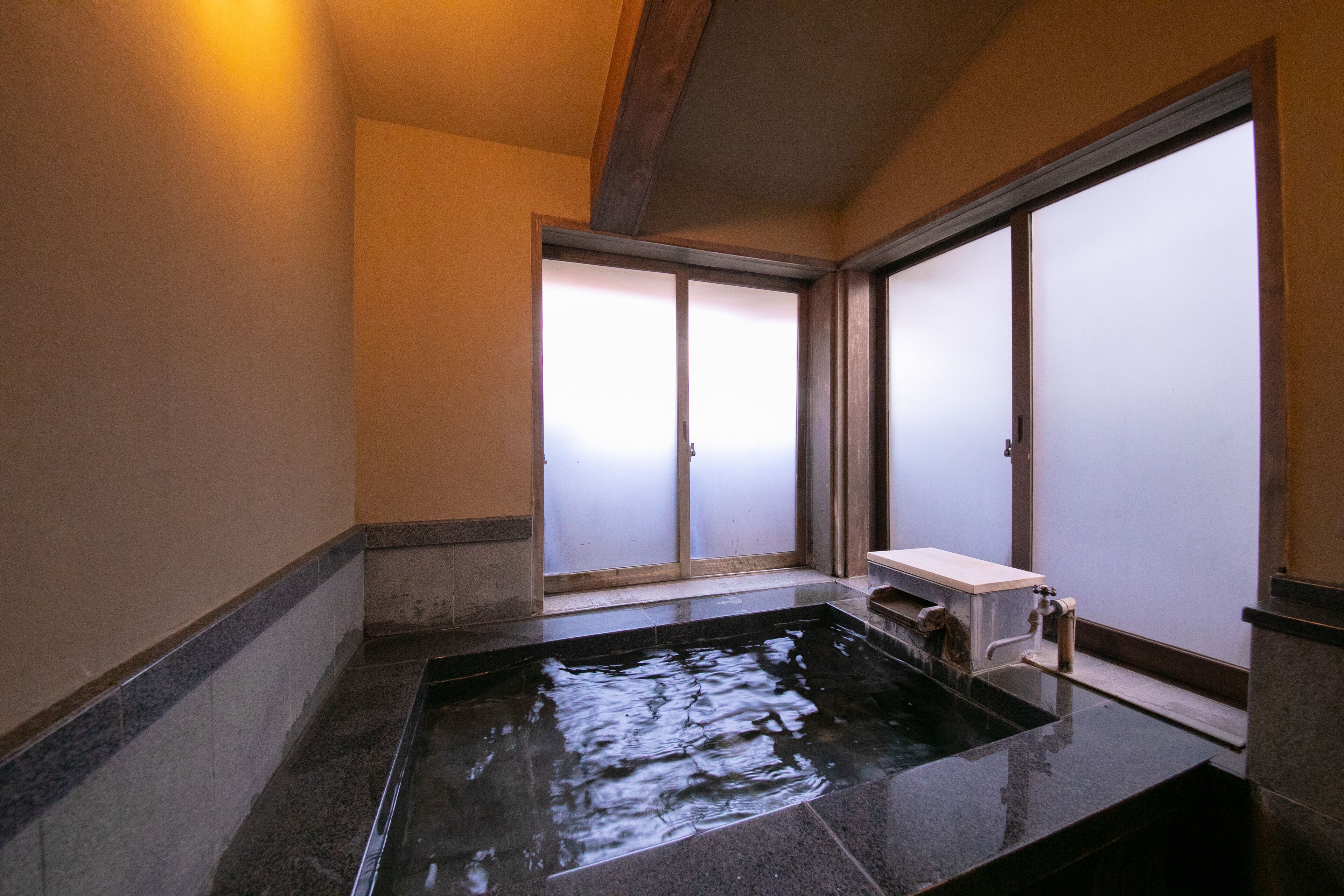A traditional Japanese room with tatami flooring, a shoji screen door, and a small wooden bench.