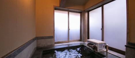 A traditional Japanese room with tatami flooring, a shoji screen door, and a small wooden bench.