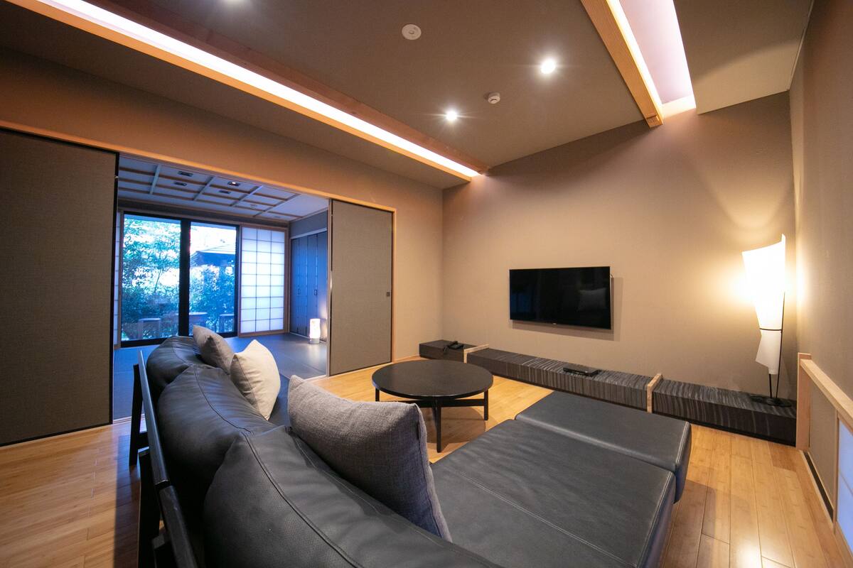 A modern living room with a sofa, a round coffee table, and a TV mounted on the wall.