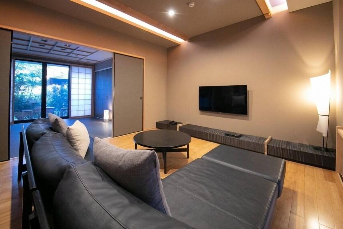 A modern living room with a sofa, a round table, and a TV mounted on the wall.