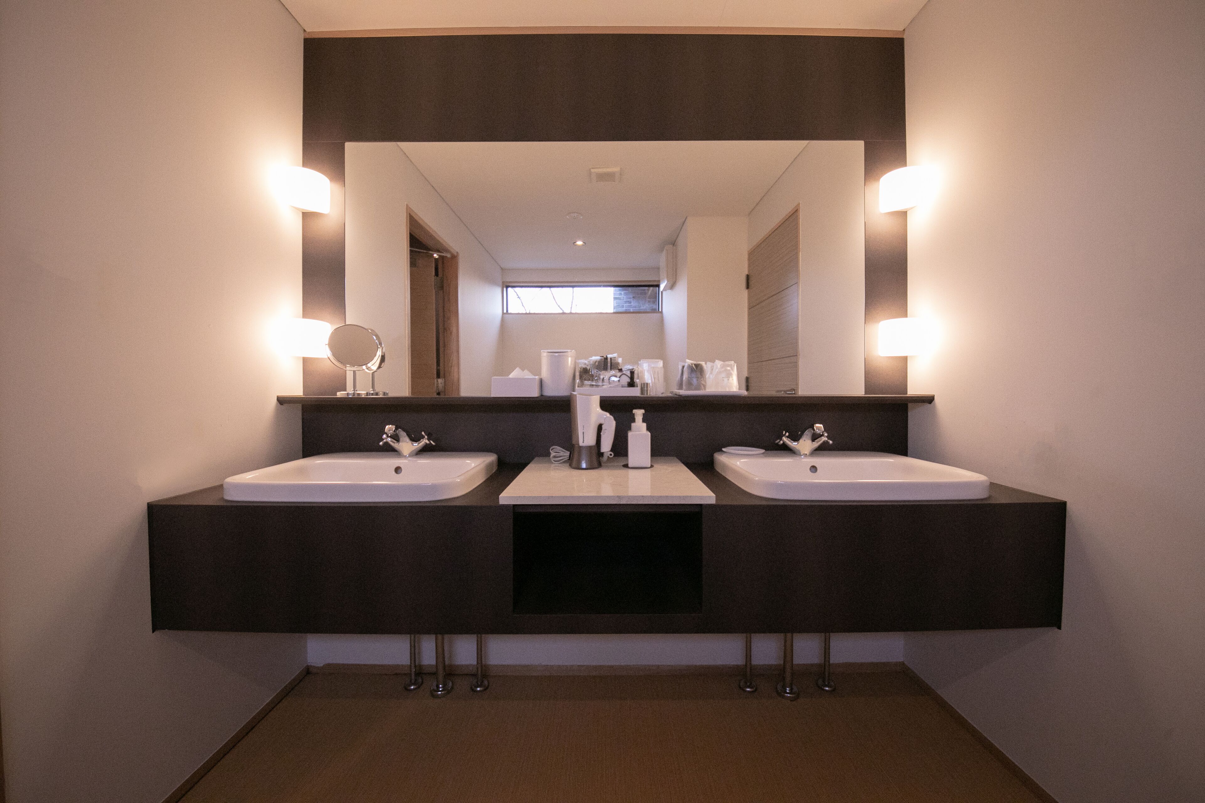 Une salle de bain moderne avec deux lavabos, un grand miroir et un éclairage au plafond.