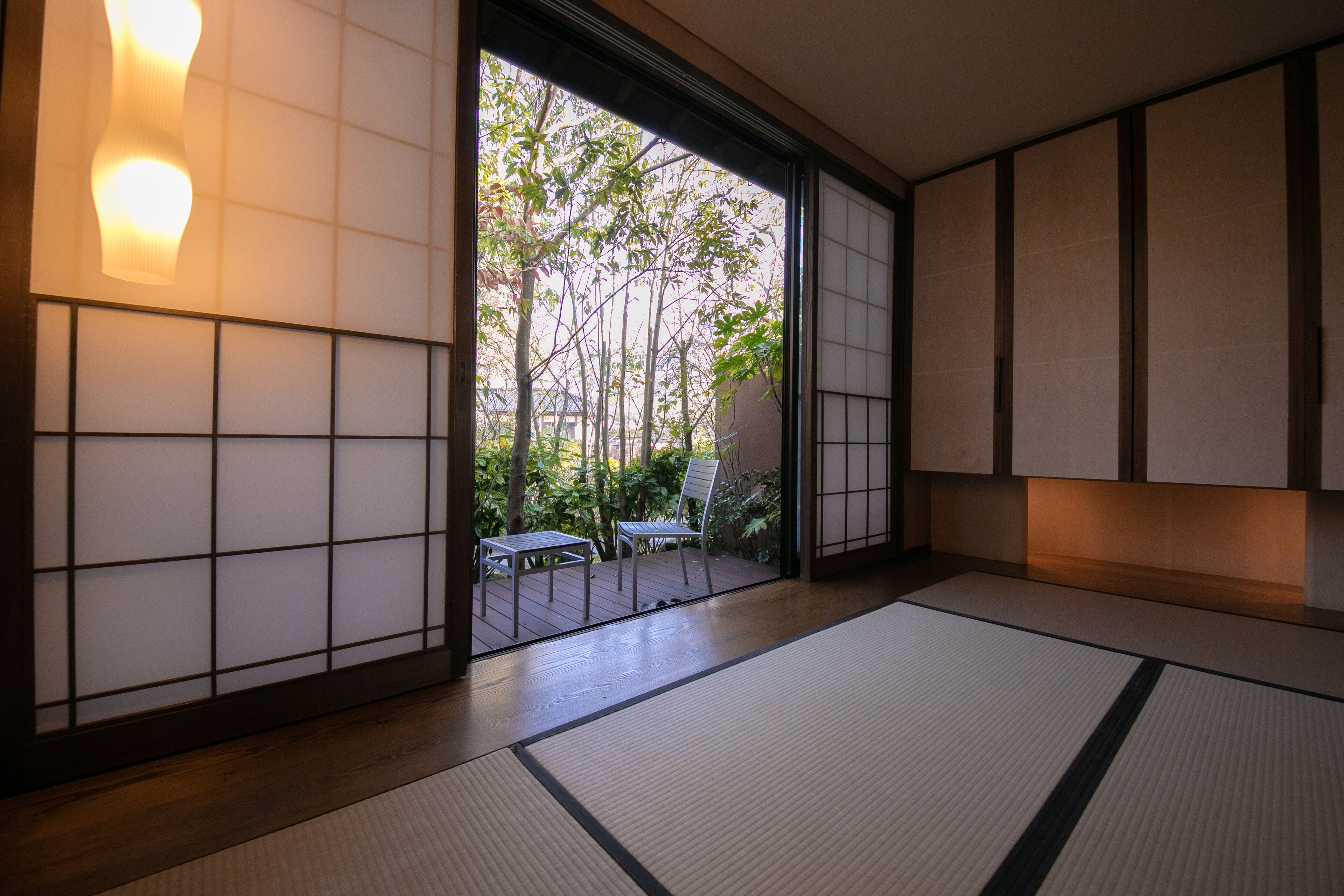 A traditional Japanese room with tatami flooring, sliding doors, and a view of a garden.
