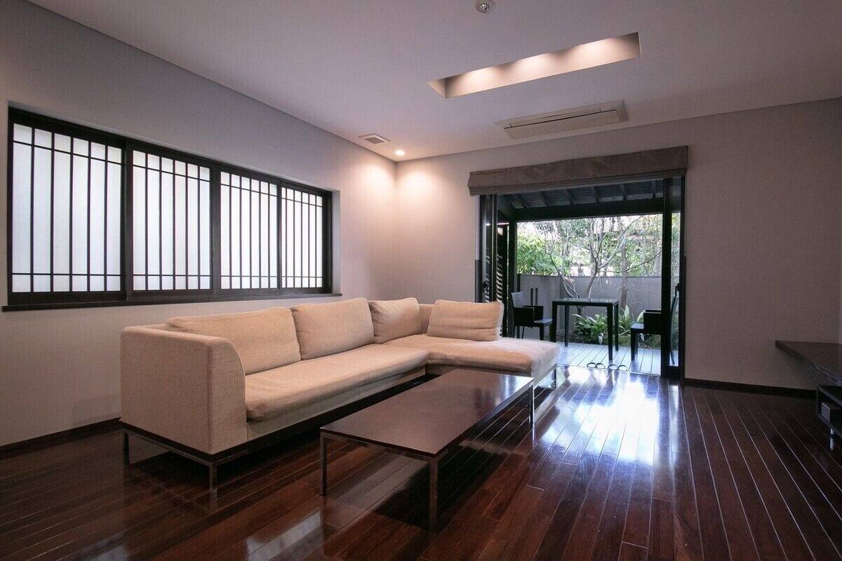 A modern living room with a sectional sofa, a coffee table, a flat-screen TV, and a sliding glass door leading to an outdoor area.