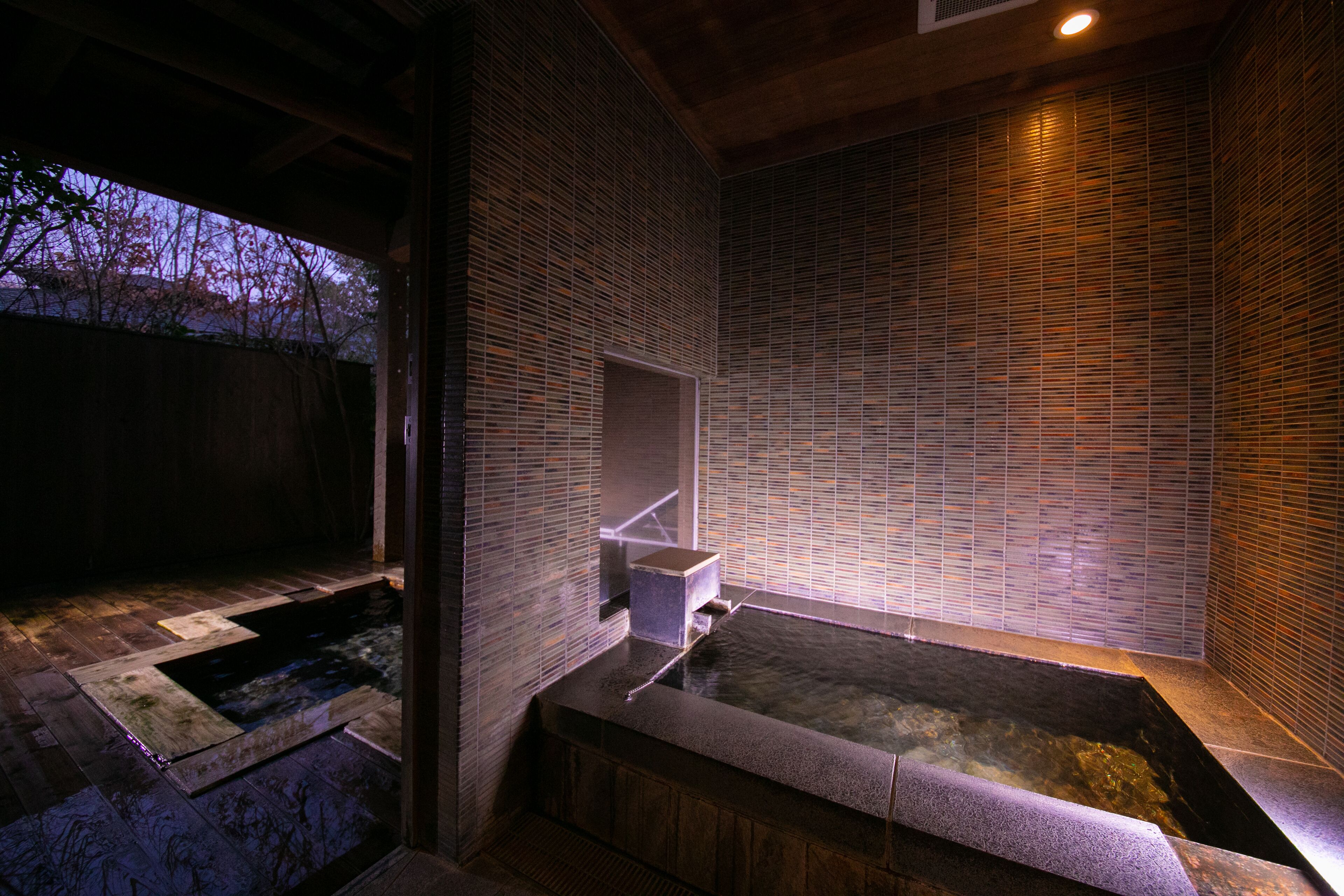 A spa area with a hot tub, wooden flooring, and tiled walls.