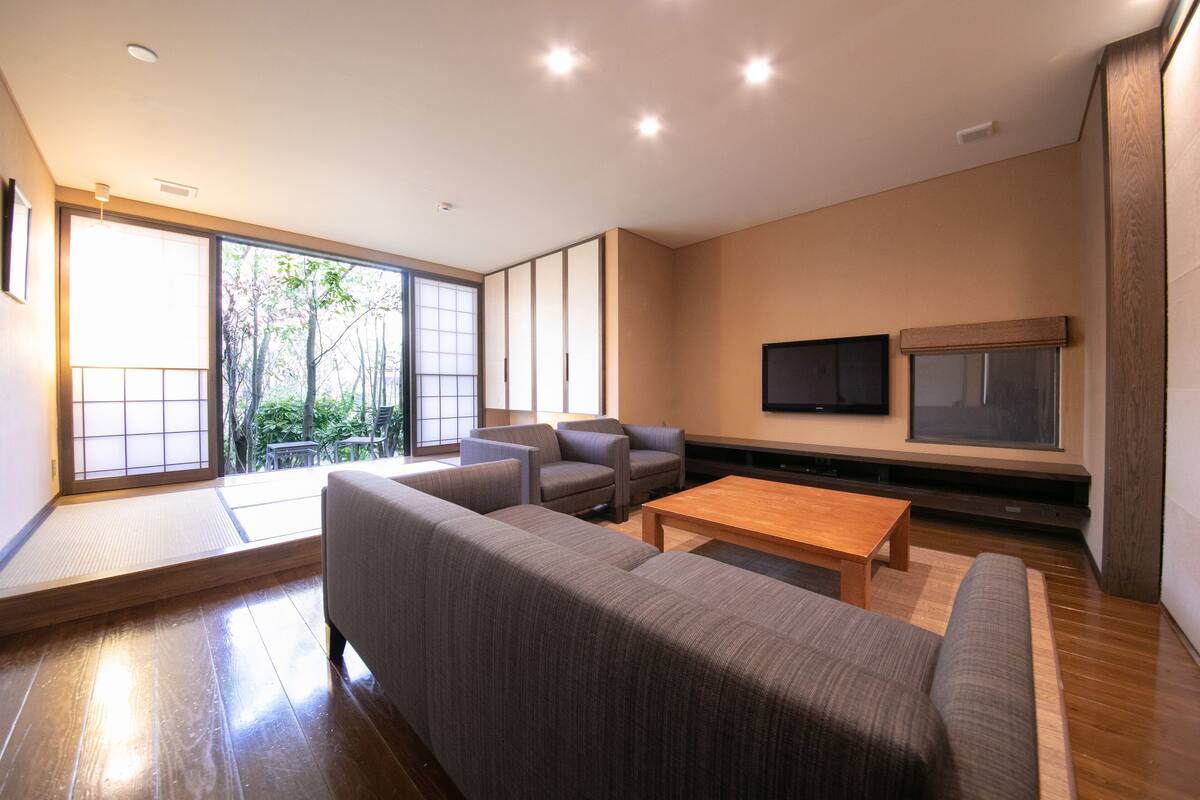 A modern living room with a sofa set, a coffee table, and a TV mounted on the wall.