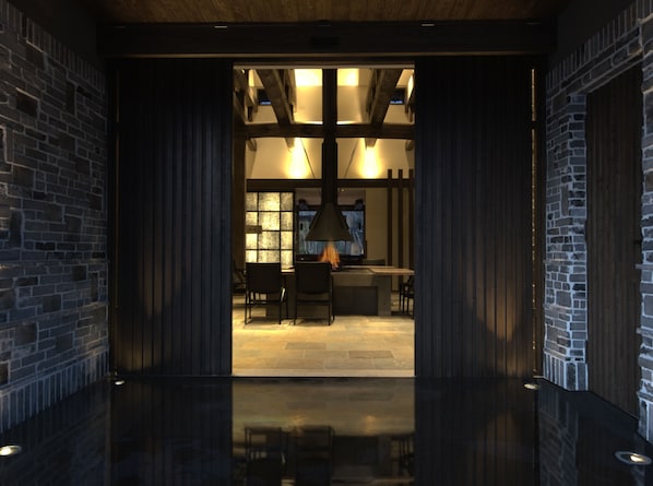 A modern interior with exposed brick walls, a wooden ceiling, and a central seating area with a table and chairs.
