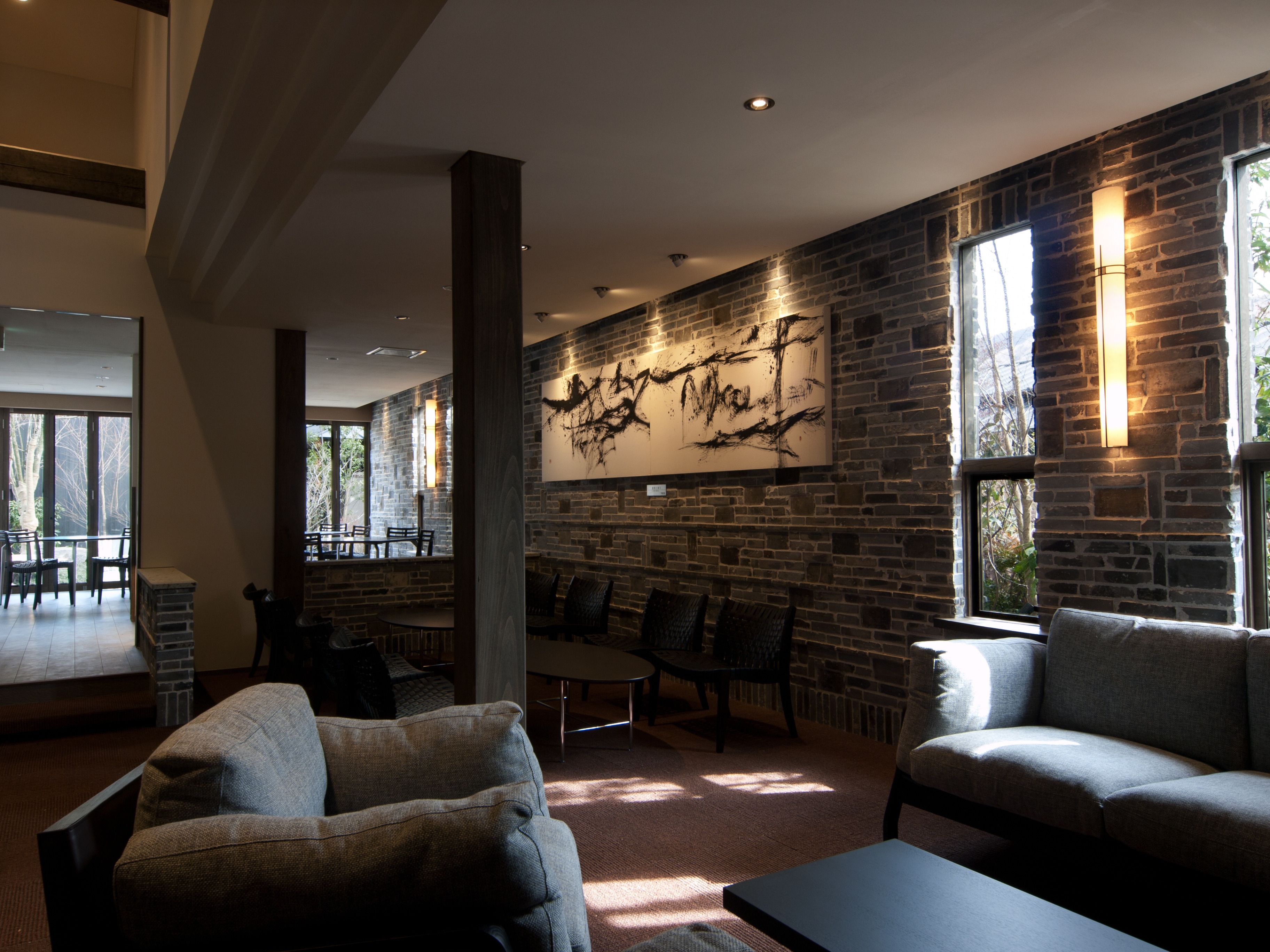Un amplio salón con pared de piedra, asientos cómodos y ventanas grandes.