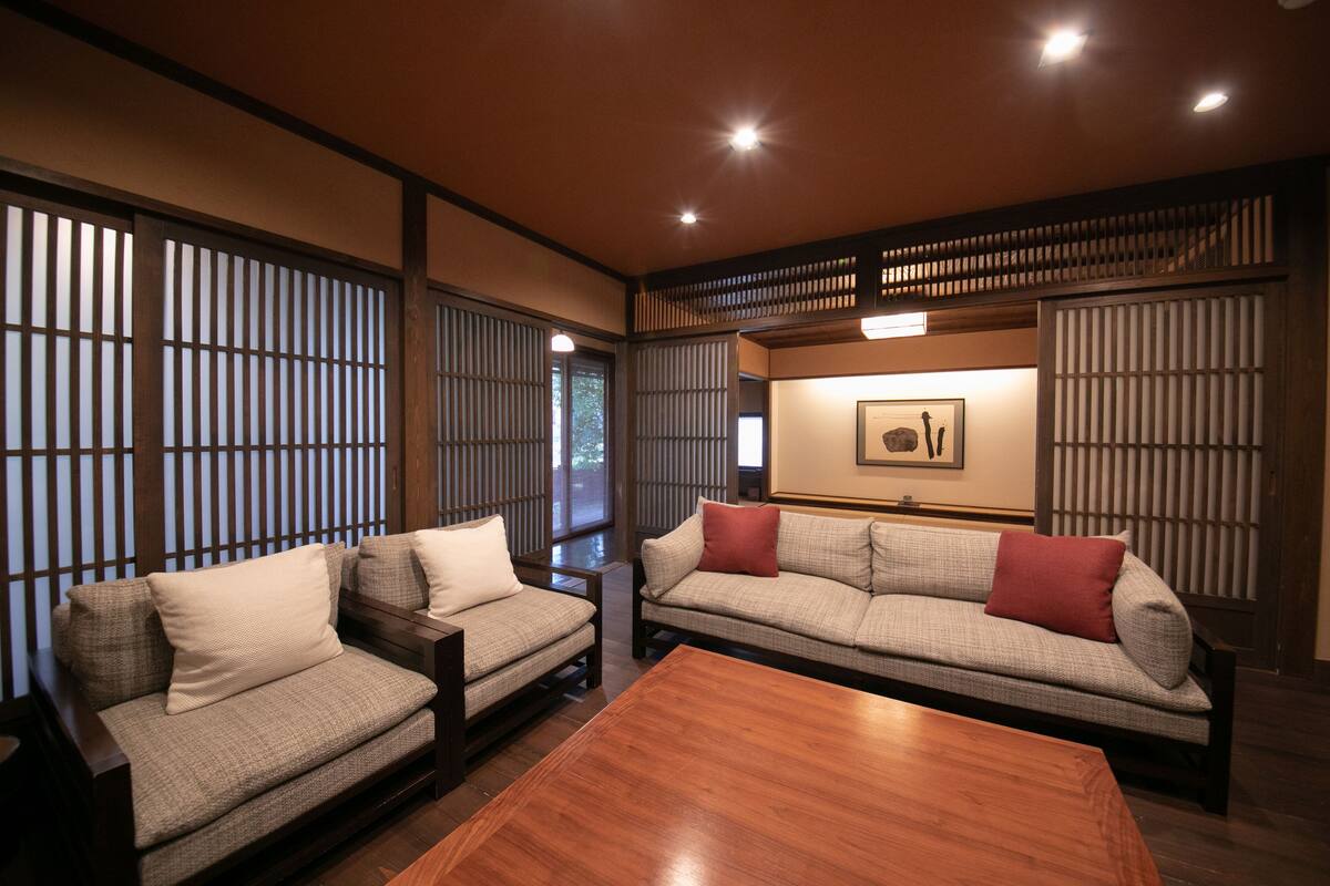 A traditional Japanese-style living room with tatami flooring, a low wooden coffee table, and two tatami mats with cushions.
