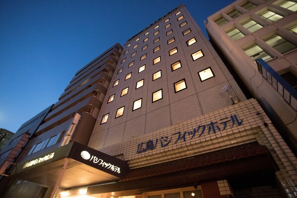 A multi-story hotel with a modern architectural design, featuring a prominent sign with Japanese characters.