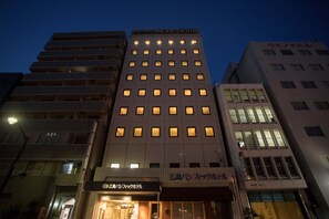 A multi-story hotel with illuminated windows and a sign reading "Tokyo Pacific Hotel".