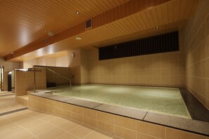 Una amplia piscina interior con techo de madera y paredes de azulejos.