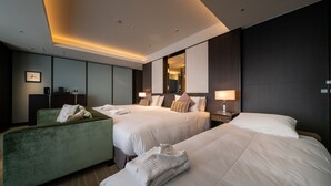 A hotel room with two beds, a green armchair, a bedside table with a lamp, and a mirror on the wall. - Hotel Allamanda Aoyama Tokyo (Tokyo)