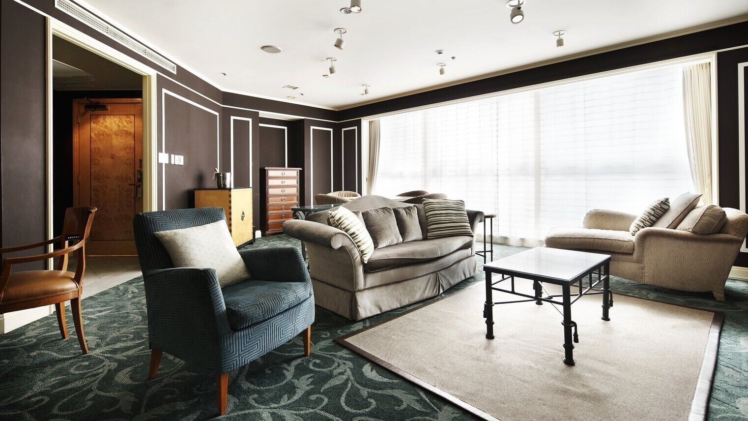 A modern living room with a sofa, armchairs, a coffee table, and a large window.