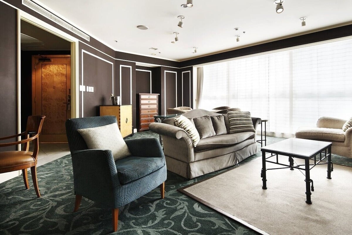A modern living room with a sofa, armchairs, a coffee table, and a large window.
