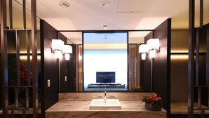 A modern bathroom with a large mirror, a sink, and wall-mounted lights. - Hotel Allamanda Aoyama Tokyo (Tokyo)