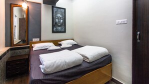 A hotel room with a bed, a mirror, a Buddha painting, and a door. - Backpacker Panda Appetite Mumbai (Mumbai)