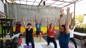 A group of people doing yoga in an outdoor setting with exercise mats and a wall with graffiti. - Backpacker Panda Appetite Mumbai (Mumbai)