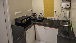 A compact kitchen with a microwave, coffee maker, and a coffee machine. There are cabinets and a sink. - Backpacker Panda Appetite Mumbai (Mumbai)