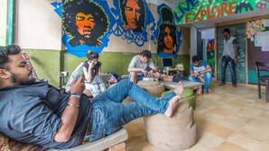 A group of people sitting on bean bags in a room with colorful murals and a 'Travel Explore' sign. - Backpacker Panda Appetite Mumbai (Mumbai)