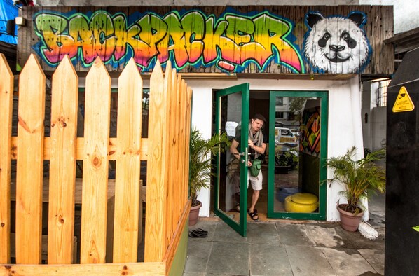 A wooden fence, a storefront with graffiti, and a person entering.