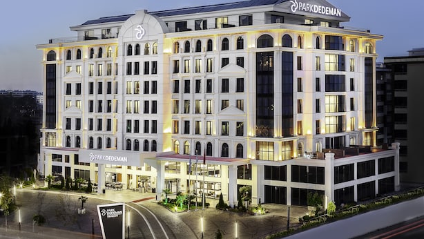 Um hotel com vários andares e design arquitetônico clássico, com entrada imponente, grandes janelas e um terraço no telhado.