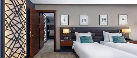 A hotel room with two beds, a wooden partition with a geometric design, and framed artwork on the wall.