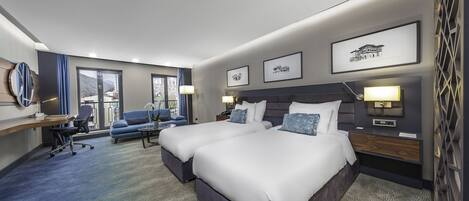 A modern hotel room with two beds, a desk, a chair, and a sofa.