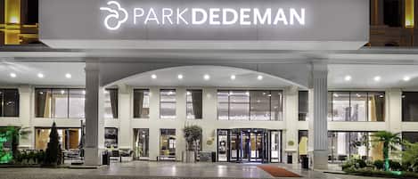 A hotel entrance with a large illuminated sign reading "PARKDEDEMAN".