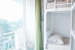Habitación con literas y vista a árboles por la ventana.