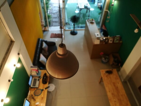 Overzicht vanuit de lucht van een kamer met een hanglamp, een houten tafel en een groene muur.