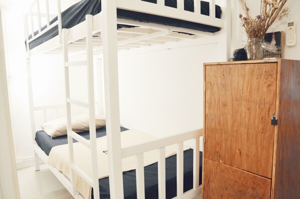 Una cama litera con un armario de madera a un lado.