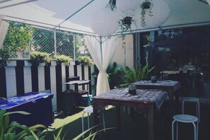 Un patio al aire libre con mesas y sillas, una mesa azul y plantas colgantes.