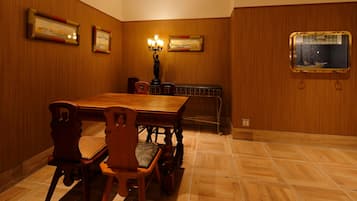 Un comedor con una mesa y sillas de madera, obras de arte enmarcadas en las paredes y un barco en la ventana.