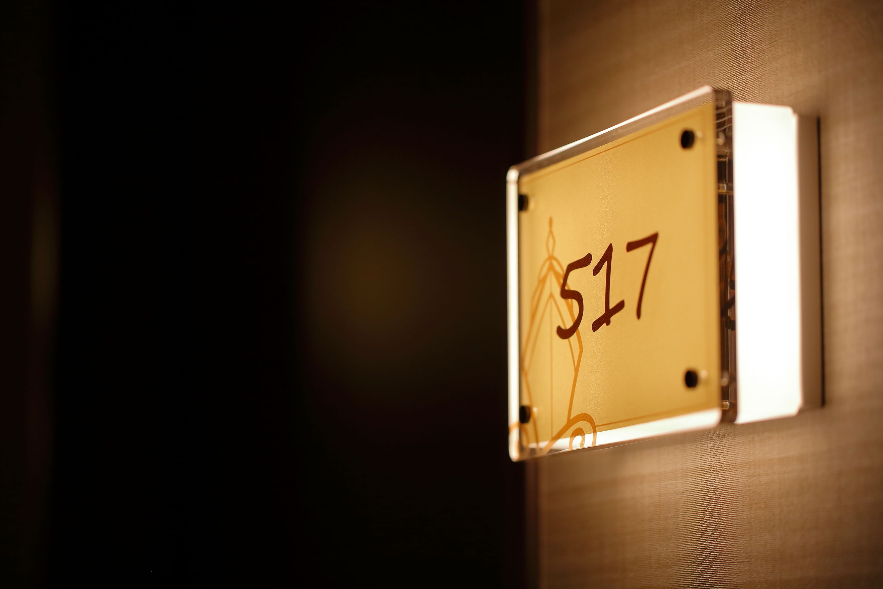 Primer plano de una placa con el número de habitación '517' fijada a la pared.