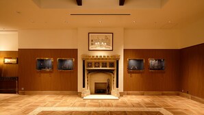 Una habitación amplia con chimenea, paneles de madera y obras de arte enmarcadas en las paredes.