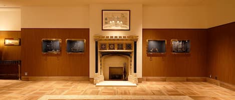 Una habitación amplia con chimenea, paneles de madera y obras de arte enmarcadas en las paredes.