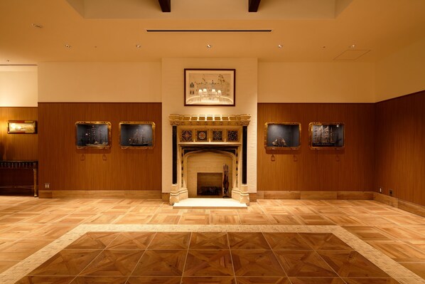 A spacious room with a fireplace, wooden paneling, and framed artwork on the walls. - Hotel Monte Hermana Kobe Amalie (Kobe)