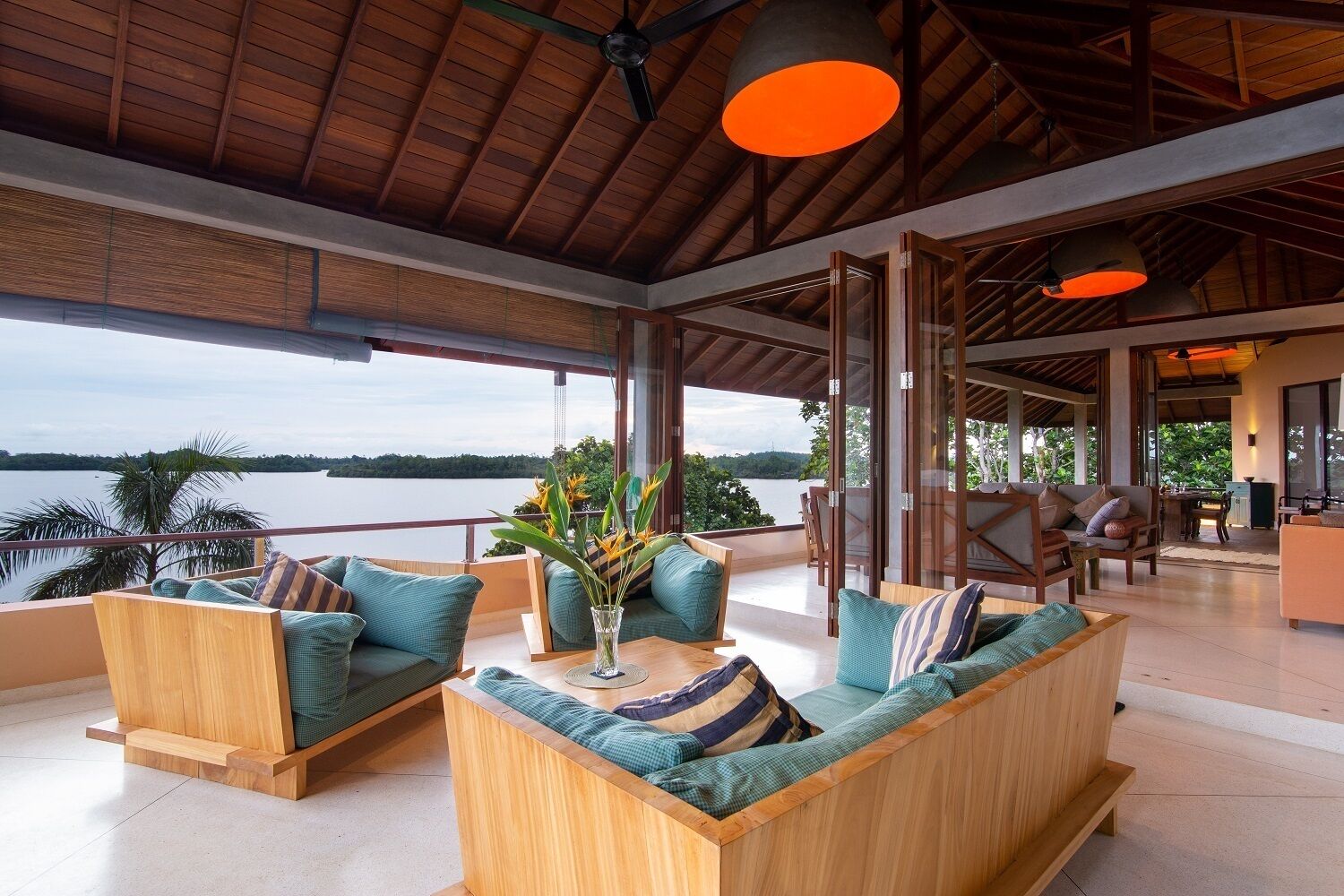 A spacious outdoor seating area with wooden furniture and a view of a lake.