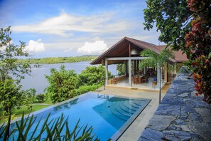 Een buitenzwembad, een infinitypool en ligstoelen