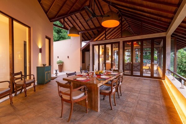 A spacious dining area with a long wooden table, multiple chairs, and pendant lighting. - Sea Heart House on Koggala Lake (Koggala)