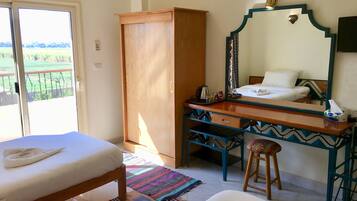 A bedroom with a bed, a desk, a wardrobe, and a bathroom mirror.