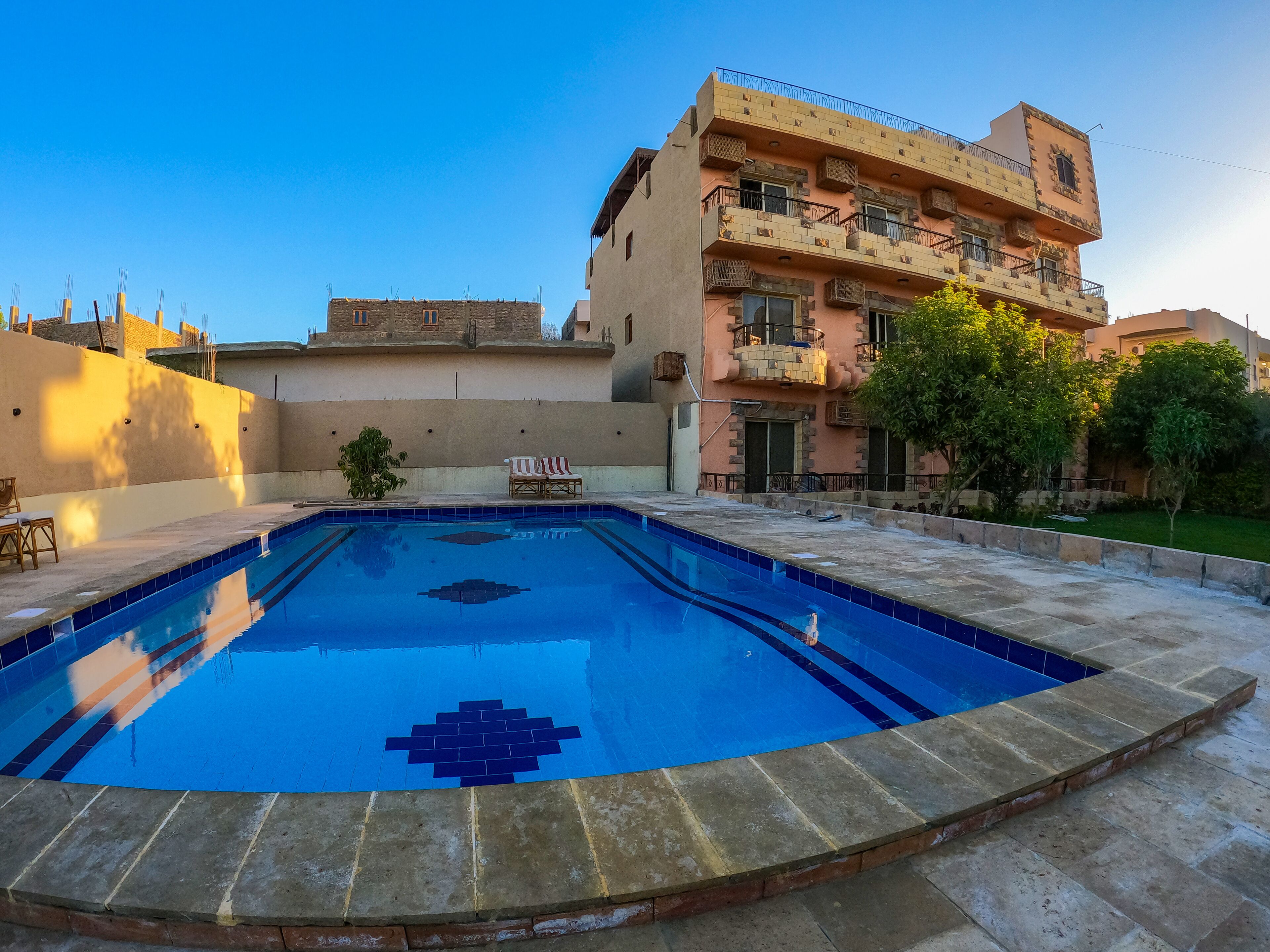 A swimming pool with a geometric tile pattern, surrounded by a stone deck.