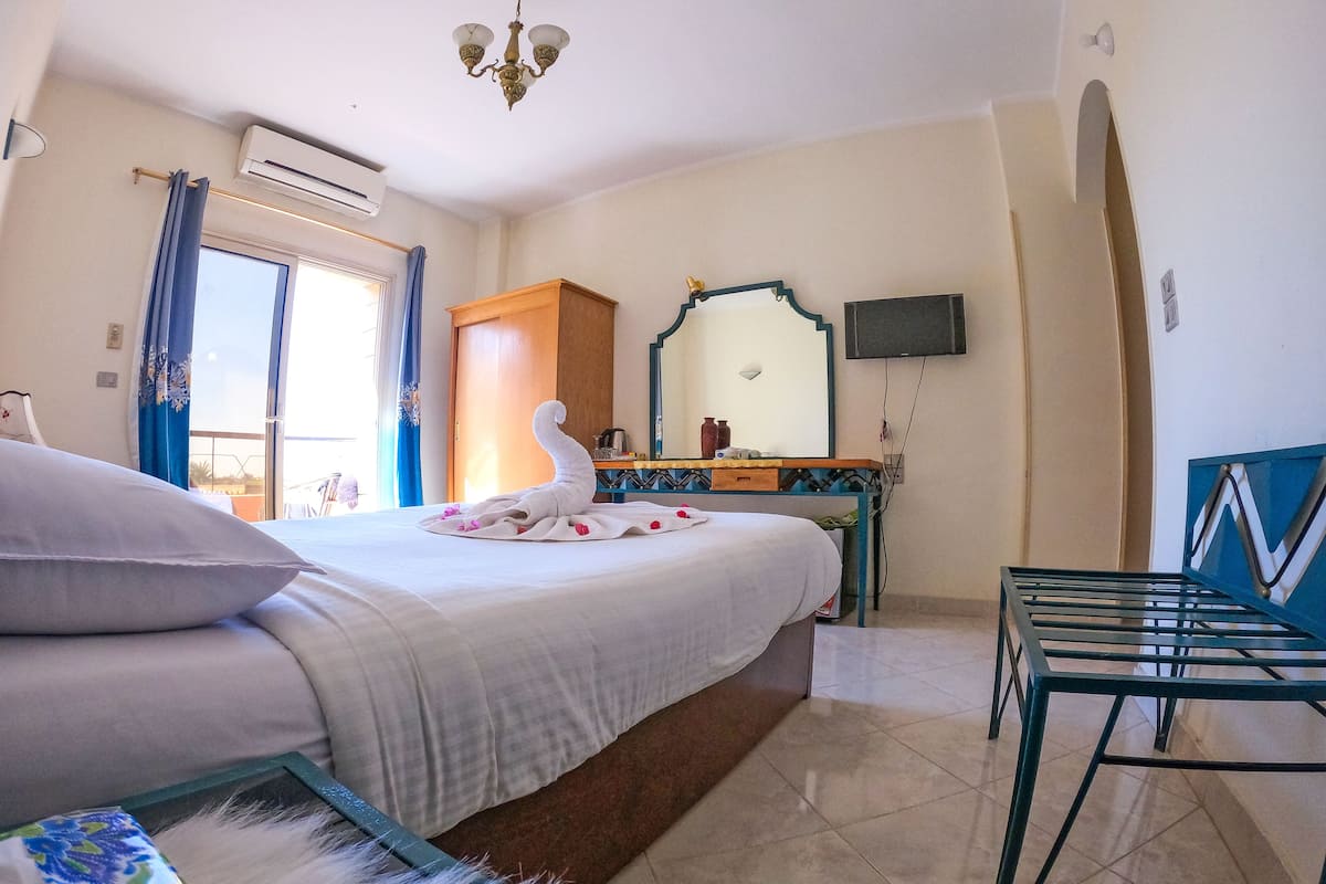 A hotel room with a bed, a desk, a chair, a television, and a window with curtains.