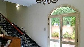 Una escalera con barandales decorados que lleva a una puerta con un panel de vidrio.