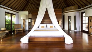 A large bed with a canopy in a spacious room with wooden floors and large windows.