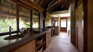 A bathroom with a large sink, wooden cabinets, and a view of greenery outside.