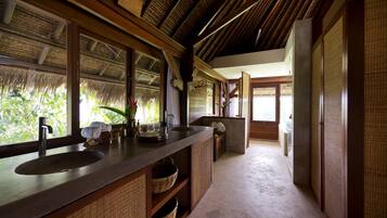 A bathroom with a large sink, wooden cabinets, and a view of greenery outside.