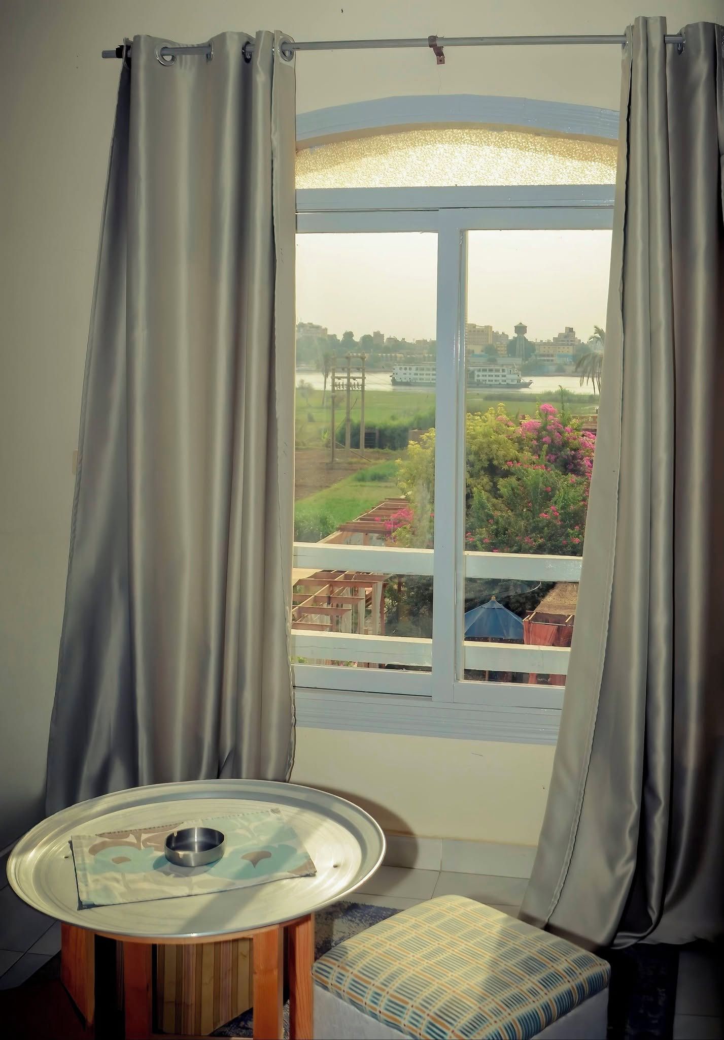 Una habitación con ventana que da a un río, una mesa con un bol y un banco.