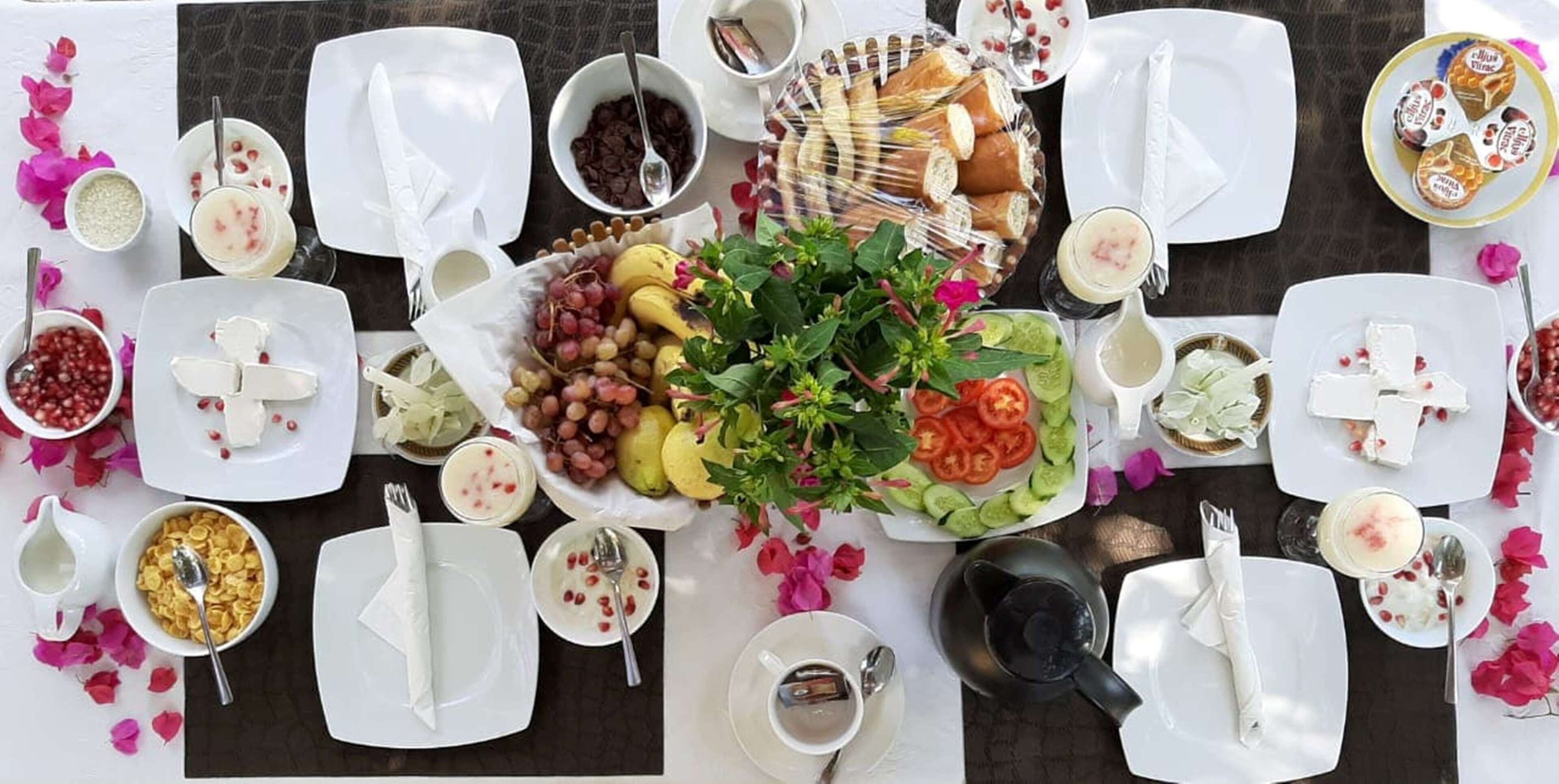 A table set for a meal with various dishes, including fruits, bread, and desserts.